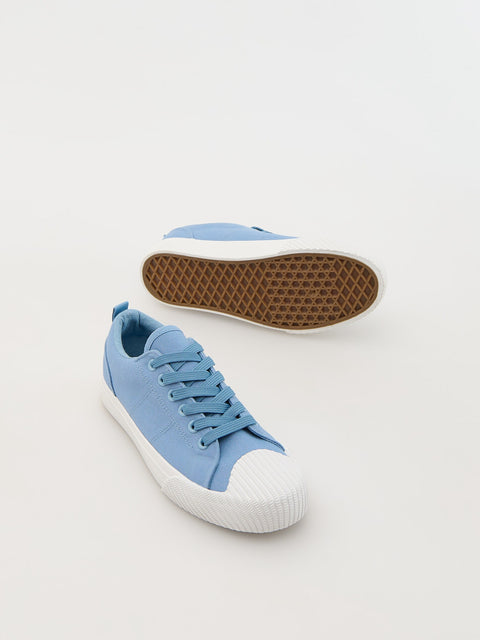 Blue sneaker with white sole on a light gray background