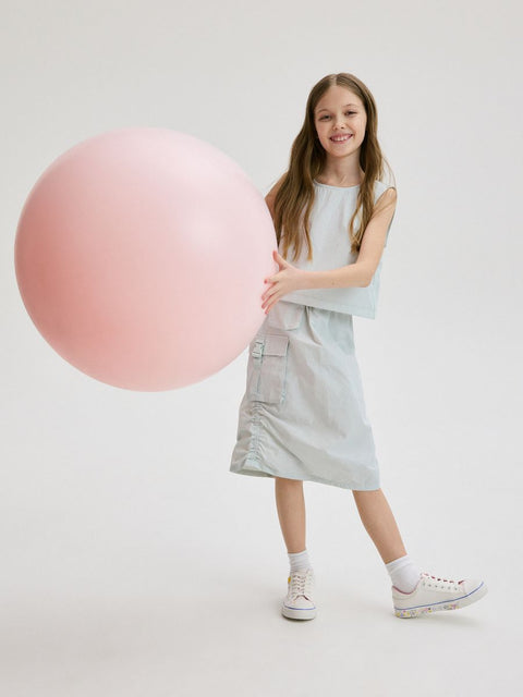Young girl holding a large pink sphere against a white background