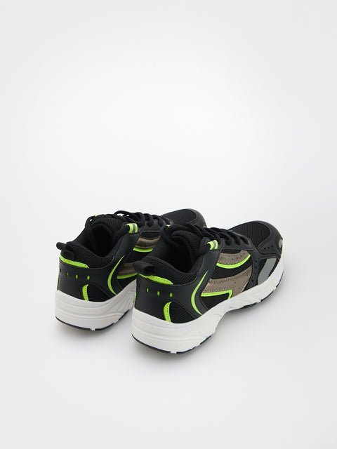 Black and green running shoes on a white background