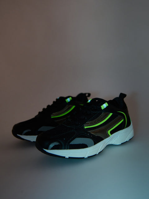 Black sneakers with green accents on a gray background