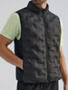 Person wearing a black puffer vest over a light green shirt on a plain background