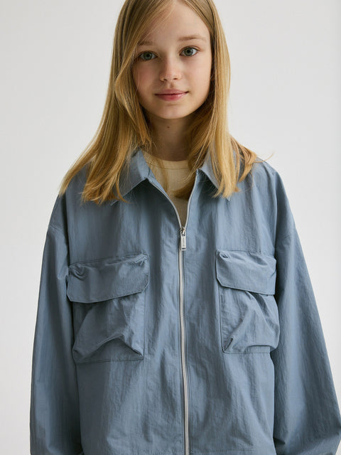 Child wearing a light blue jacket with a white background