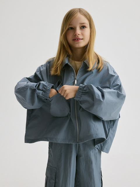 Person wearing a blue jacket and pants on a plain background
