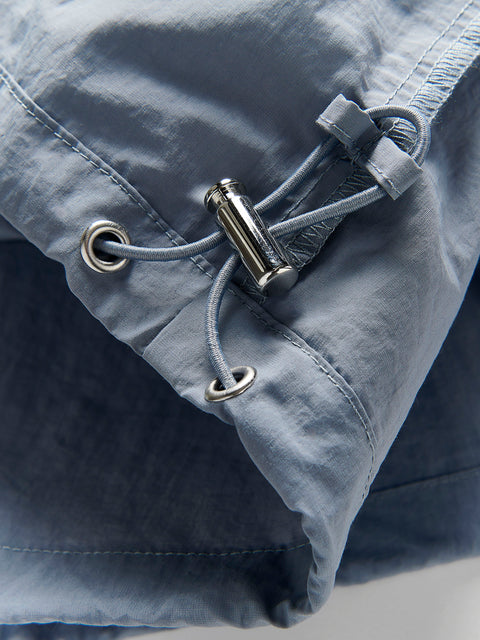 Close-up of a blue jacket with a drawstring and metal buckle on a light gray background