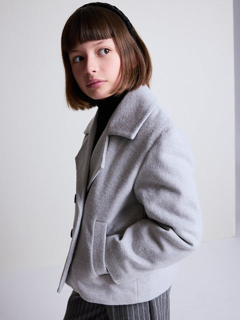 Person wearing a gray coat against a white background