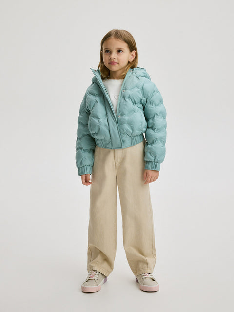Child wearing a light blue puffer jacket and beige pants on a white background
