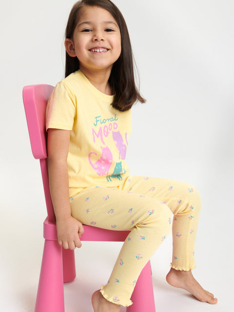 Child wearing a yellow outfit with a floral design on a white background