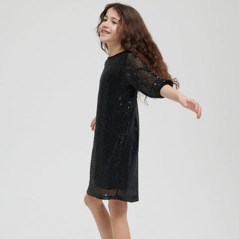 Young girl wearing a black sequin dress on a white background