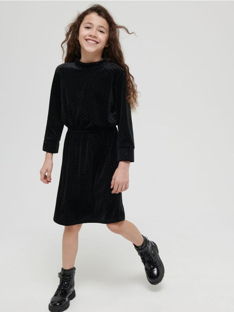 Young girl wearing a black dress with long sleeves on a white background