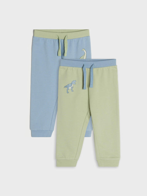 Two pairs of children's jogger pants, one blue and one green with a dinosaur design, on a light gray background.