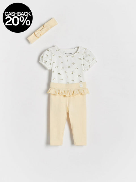 Baby outfit with floral top and yellow pants on a light gray background