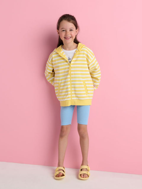 Young girl wearing a yellow and white striped hoodie against a pink background