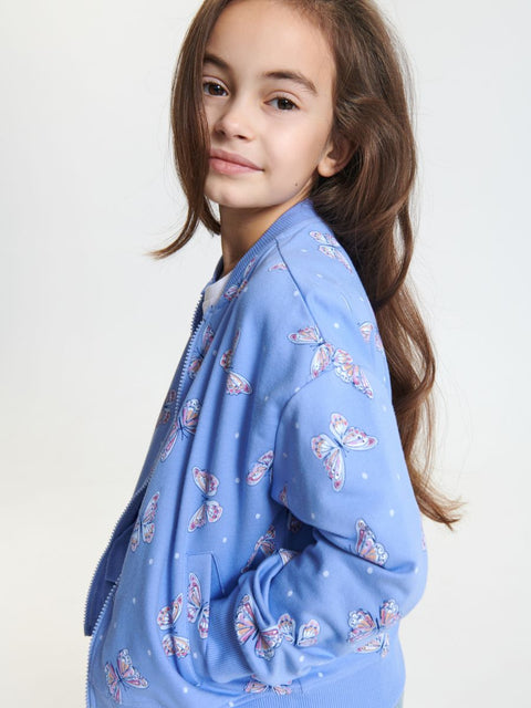 Young girl wearing a blue patterned jacket on a white background