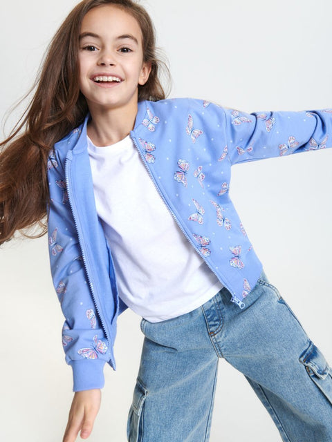 Child wearing a light blue jacket with floral patterns, white shirt, and blue jeans on a white background