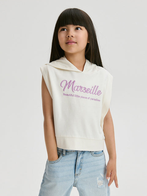 Young girl wearing a sleeveless hoodie with 'Marseille' text on a plain background