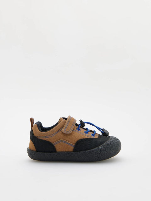 Children's shoe with brown, black, and blue design on a white background