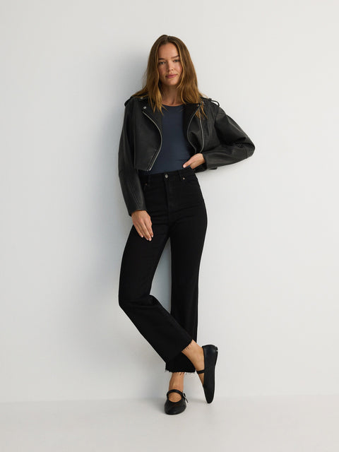 Woman wearing a black leather jacket and black pants on a white background