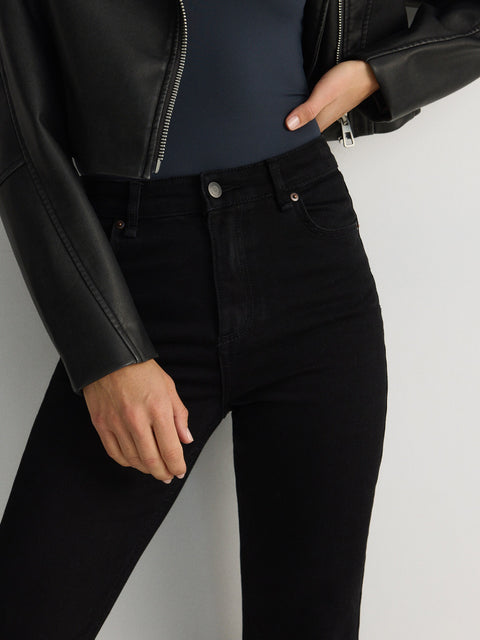 Person wearing a black leather jacket and black jeans on a white background