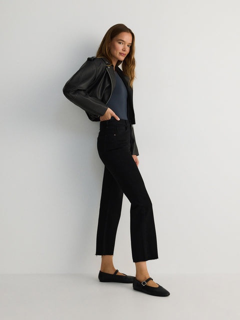 Woman wearing a black leather jacket and black pants against a white background