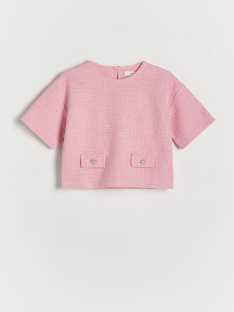 Pink blouse with short sleeves and two front pockets on a light gray background