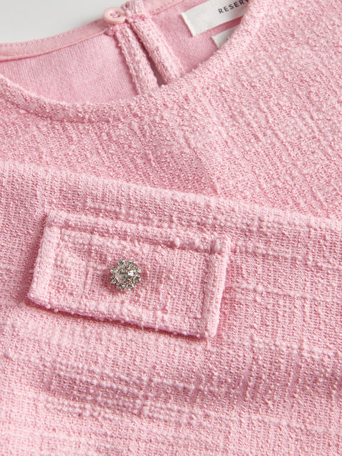 Close-up of a pink textured garment with a decorative button.