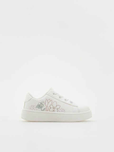 White sneaker with floral embroidery on a white background