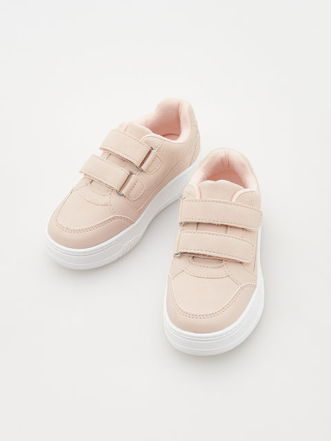 Pair of light pink sneakers with white soles on a light gray background