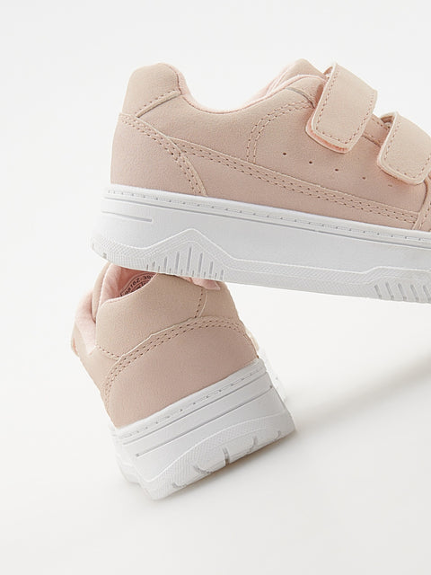 Pair of pink sneakers with white soles on a light gray background