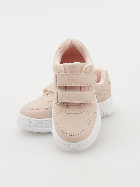 Pair of light pink sneakers with white soles on a light gray background