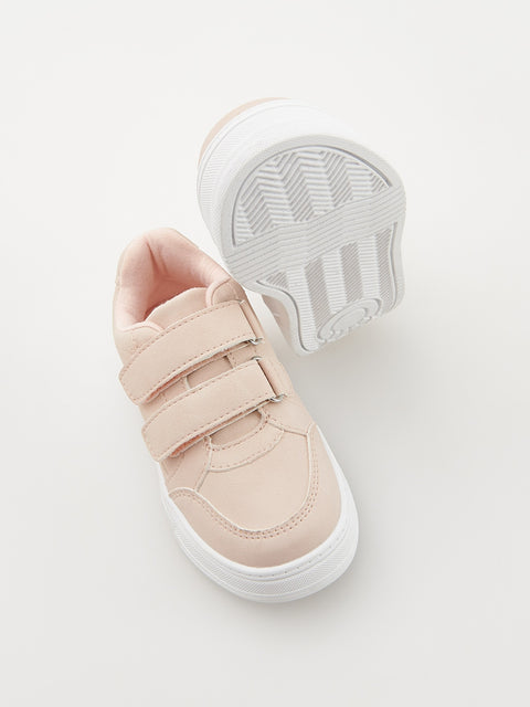Pink children's sneakers with velcro straps on a white background