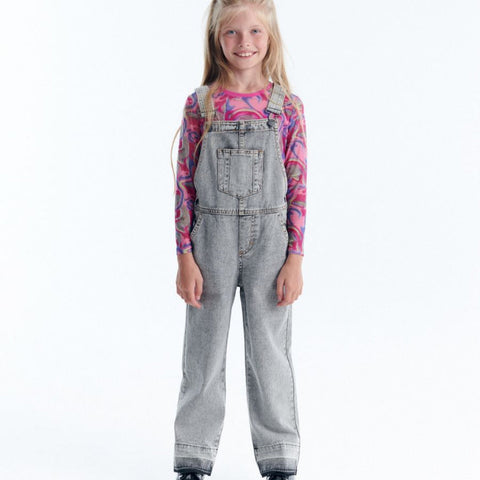 Young girl wearing gray denim overalls on a white background