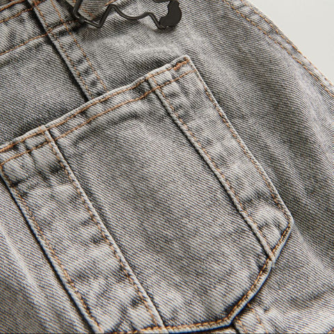 Close-up of a denim pocket with stitching details on a light gray background