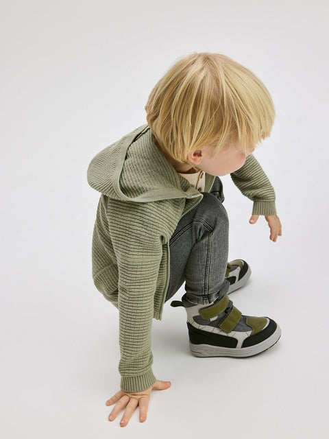 Child wearing a green knitted outfit on a white background