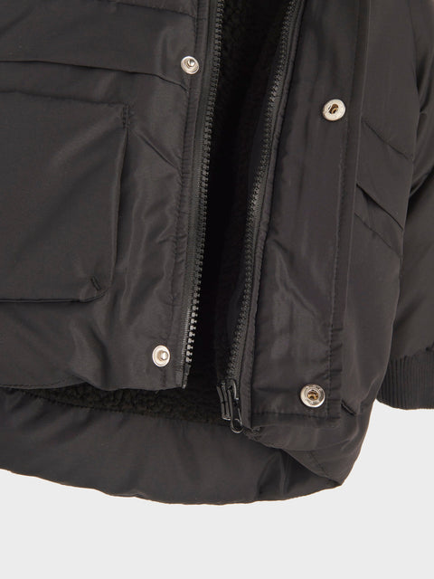 Close-up of a black jacket with zippers and buttons on a light gray background