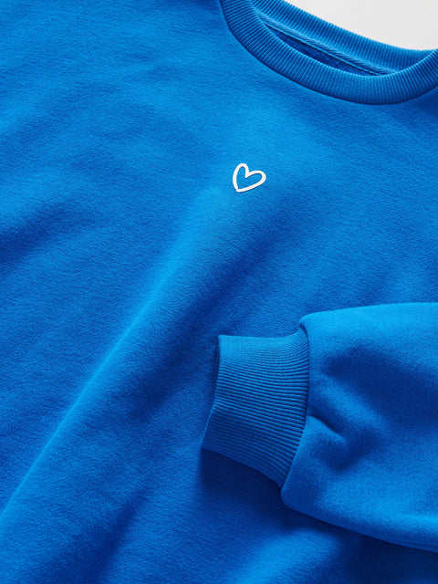Close-up of a blue sweatshirt with a white heart design on a light gray background