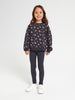 Young girl wearing a navy sweatshirt with pink floral pattern and leggings on a white background