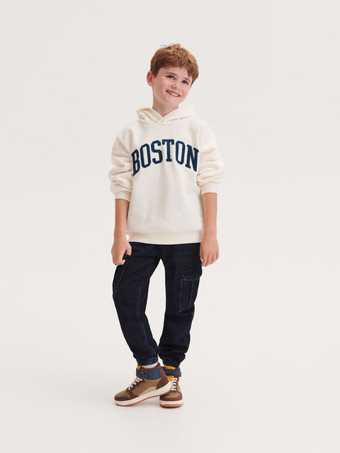 Child wearing a 'Boston' hoodie on a white background