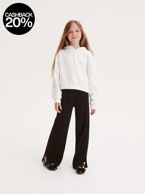 Young girl wearing a white hoodie and black pants on a white background