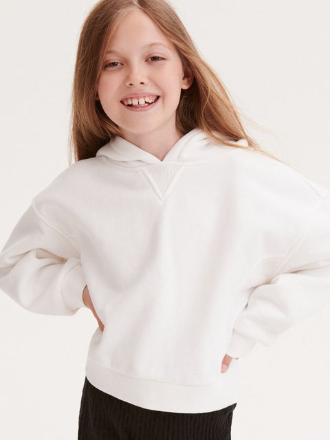 Young girl wearing a white hoodie against a plain background
