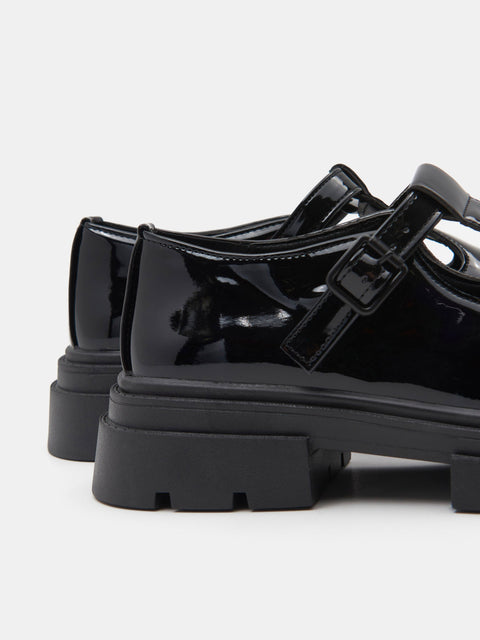 Black patent leather shoes with thick soles on a white background
