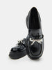 Black glossy loafers with a decorative bow and pearls on a white background