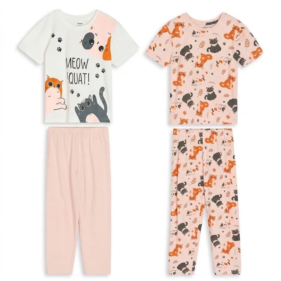Two children's short-sleeve pajama sets shown on a plain white background. The left set has a white top with cat illustrations and the text 'MEOW QUAT!' paired with light pink pants.