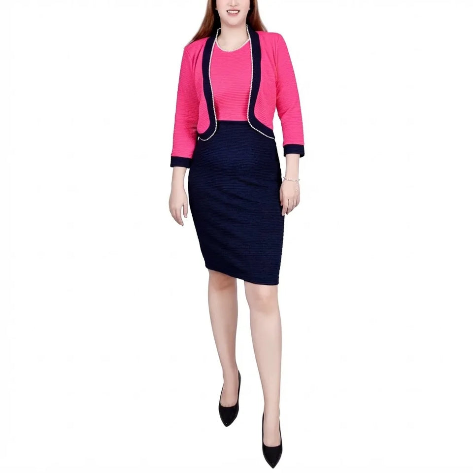 A woman modeling a two-piece outfit consisting of a bright pink cropped jacket with dark navy trim over a matching pink top and a dark navy textured pencil skirt, paired with black heels, on a plain white background.