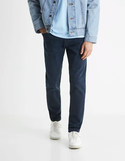 Person wearing navy pants, light blue shirt, and denim jacket on a white background