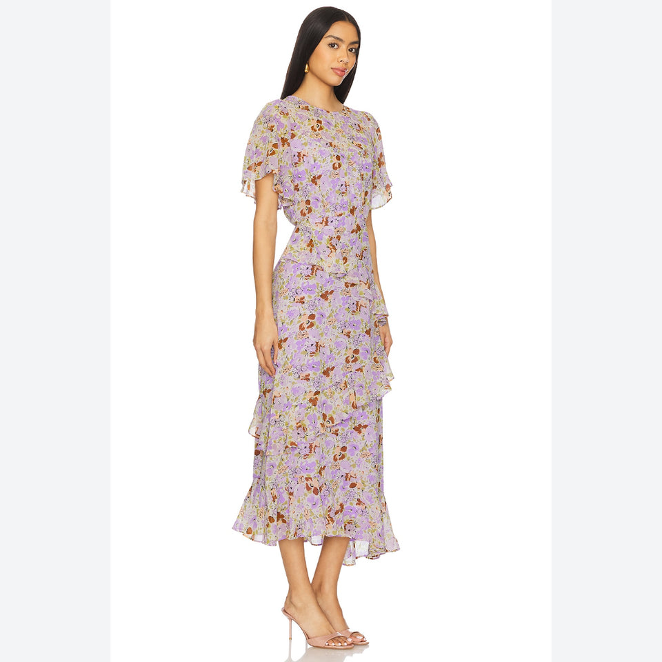 A woman modeling a light purple midi dress with a dense multicolor floral print, featuring short flutter sleeves and a ruffled hem, set against a plain white background.