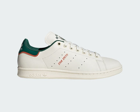 White Adidas sneaker with green and red accents on a light gray background