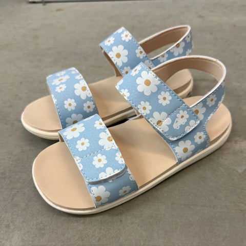 Pair of sandals with floral straps on a concrete floor
