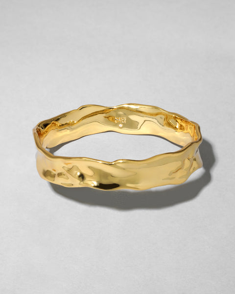 Gold ring with a textured design on a light gray background
