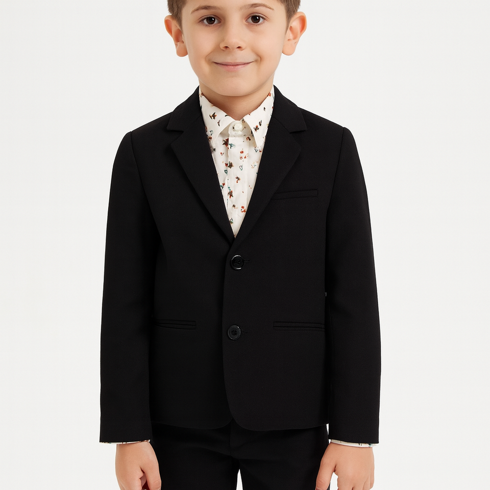 Young boy wearing a black suit jacket over a patterned shirt on a white background