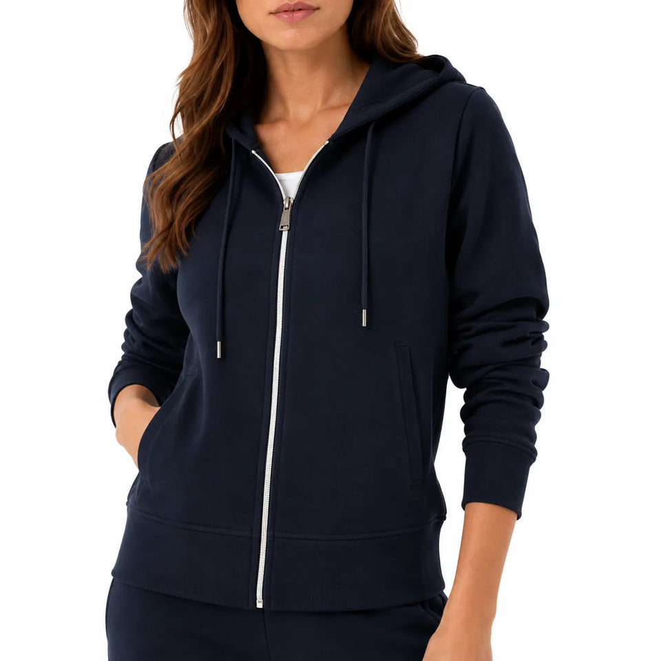 A woman wearing a navy blue zip-up hoodie with a white zipper and matching navy sweatpants, shown from the neck down against a plain white background.